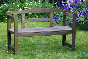 Drewniana ławka ogrodowa. Piękny ogród z drewnianymi meblami. Mała architektura ogrodowa.