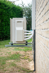 New air-source heat pump installed outside family home, air conditioning mounted on wall of new building