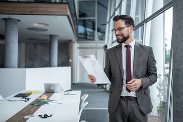 Fototapeta premium Smiling businessman reading documents in modern office