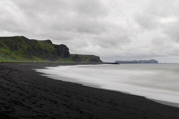 Cloudy view of black sand beach in Vik during the day.