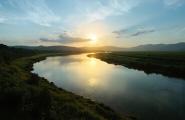 Fototapeta premium Golden sun sets over calm river, reflecting warm light on tranquil water. Rich green banks and distant hills create serene natural landscape. Dusk sky with light clouds adds to peaceful atmosphere.