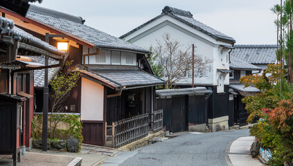 The historic streetscape of Saga-Toriimoto, a preserved district on the Atago Kaido road, with traditional machiya houses and autumn foliage. Kyoto, Japan
