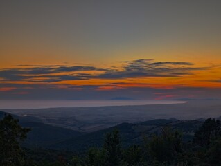 Dramatic sunrise over a foggy mountain valley in the Italian countryside of Allumiere