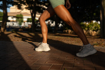 Close-up of a fit athletic woman’s legs during a workout in the park, wearing light green shorts...