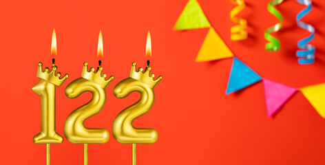 Number 122 birthday candle on an orange background with pennants