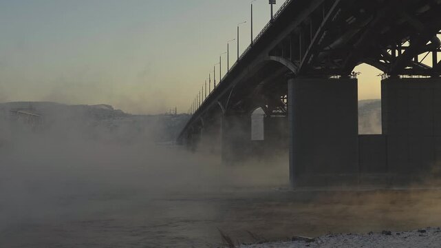 Silhouetted Bridge Over a Foggy River at Dawn