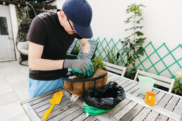 One man plants a flower in a pot in the backyard.