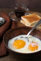 Traditional asian breakfast with half-boiled eggs in bowl, coffee and toasted bread on wooden table, closeup