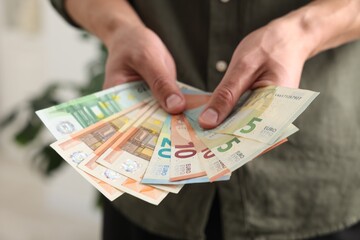 Man counting his money indoors, closeup view