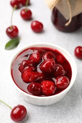 Tasty cherry jam and fresh fruits on light table, closeup