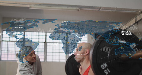 Spotting trainer assisting man in red tank top performing barbell squat in gym with digital overlay