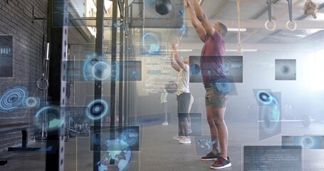 Hoisting med balls overhead, group in sportswear training at gym with pull-up rig, UI overlays