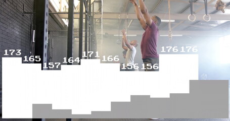 Reaching training partners pulling metal pull-up rig in fitness gym, with rings and plyo box