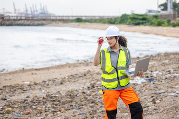 Environmental Engineer Inspecting Coastal Area with Laptop, Female Scientist Monitoring Pollution Levels on a Beach, Worker in Safety Vest and Hard Hat Examining a Contaminated Shoreline