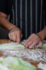 Hands covered in flour cutting unique green gnocchi dough
