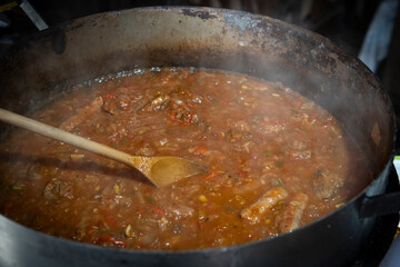 Stirring a rich, savory meat sauce in a large pot