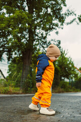 Fototapeta premium An adorable little toddler dressed in vibrant rain gear is joyfully exploring the great outdoors on a rainy day, stepping in puddles and enjoying the beauty of nature all around them