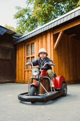 A Joyful Child Enthusiastically Riding a Vintage Toy Motorcycle in a Gorgeous and Serene Outdoor...