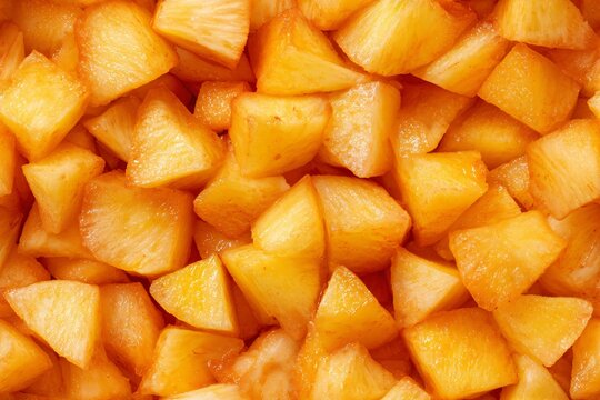 Diced pineapple pieces texture background. Sweet tropical fruit snack. Close-up food pattern idea. Good dessert ingredient.