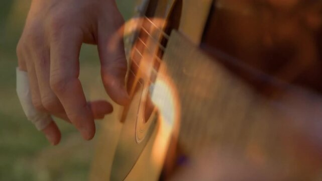 Musician plucking guitar strings in sunlit field sparking animated flame swirl around hand