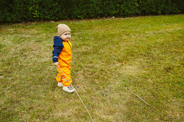 An adorable toddler dressed in bright and colorful rain gear happily explores the great outdoors...