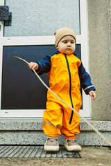 An adorable little toddler dressed in bright yellow rain gear is joyfully enjoying exciting outdoor...