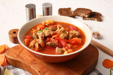 Bowl of tasty beef stew on white background