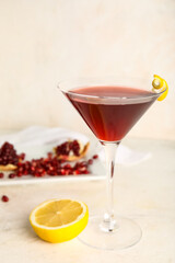 Glass of Cosmopolitan cocktail with lemon and pomegranate on white background