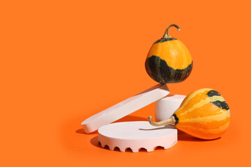 Decorative plaster podiums and pumpkins on orange background