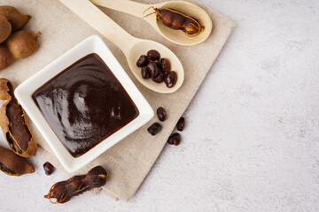 Bowl with tasty tamarind jam and fruits on white background