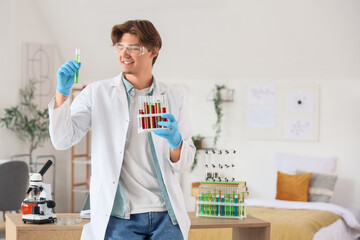 Male student in lab coat with test tubes at home