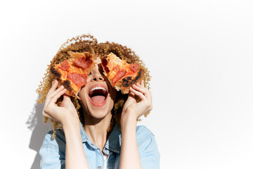 Happy woman with curly hair joyfully holding pizza slices in front of her face, celebrating food...