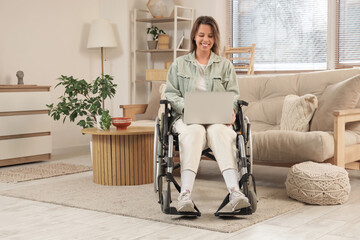 Young woman in wheelchair using laptop at home