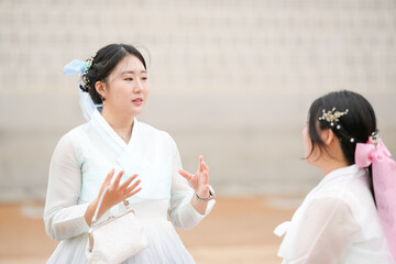 In Seoul in June 2025, two Korean women in their twenties wear pink and sky-blue hanbok as they...