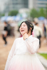 In Seoul in June 2025, a Korean woman in her twenties wearing a charming pink hanbok stands smiling...