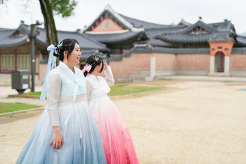 In Seoul in June 2025, two Korean women in their twenties wear pink and sky-blue hanbok as they...