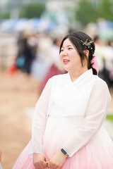 In Seoul in June 2025, a Korean woman in her twenties wearing a charming pink hanbok stands smiling...