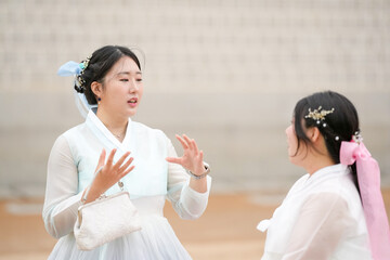 In Seoul in June 2025, two Korean women in their twenties wear pink and sky-blue hanbok as they...