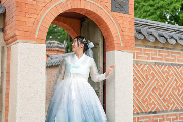 In Seoul in June 2025, two Korean women in their twenties wearing pink and sky-blue hanbok stand in...