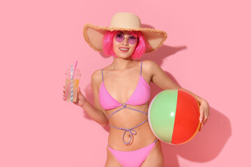 Pretty young woman in swimsuit holding plastic cup of fresh lemon cocktail with straws and beach...