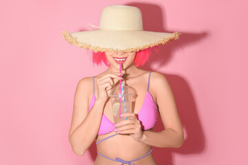 Pretty young woman in swimsuit and hat holding plastic cup of fresh lemon cocktail with straw on...