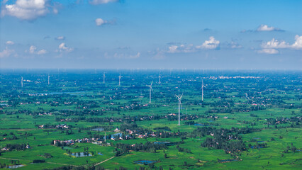 Aerial view of green fields with wind turbines in the distance