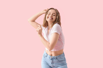 Cool young woman dancing on pink background