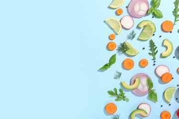 Different fresh vegetables with basil leaves, arugula and citrus fruits on blue background