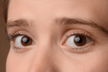 Obraz premium Woman with brown eyes on color background, closeup