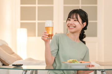 家の寝室で晩酌する若いアジア人女性（ビール,家飲み,飲酒習慣）
