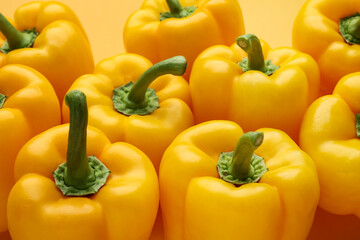 Many yellow bell peppers on color background