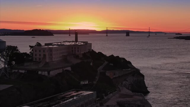 Alcatraz Island, USA, stands silhouetted against a vibrant sunset. The former prison and landmark is a popular tourist destination, offering tours and history.