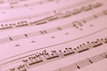 Fototapeta premium Music notes on a pink paper. Pink background and a sheet of music composition. 