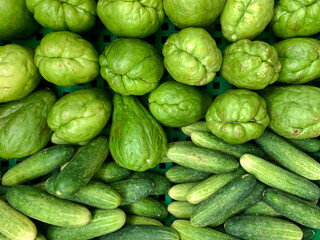 Freshly harvested tropical chayotes and cucumbers displayed in the market